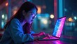 © Viktor - Young woman types on laptop in neon light. Night city background blurred. Colorful screen illuminates face. Focus on coding or digital art. Inspiring creative workspace.