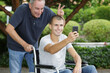 © auremar - dad and son in wheelchair taking selfie in the park