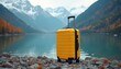 © Viktor - Yellow suitcase rests on rocky shore of mountain lake. Autumn trees reflect in calm water. Snowy peaks rise in background. Ready for adventure.