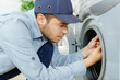 © auremar - working man plumber repairs a washing machine in laundry