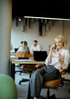 © BGStock72 - Woman talking on a phone in an office while others work at their desks