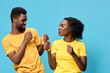 © SHOTPRIME STUDIO - Happy couple dancing together in matching yellow outfits against a vibrant blue backdrop, expressing joy and connection through movement and laughter