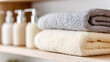 © BetterPhoto - Stacked soft towels beside skincare pump bottles on bathroom shelf, spa wellness and self-care concept, clean minimal interior with gentle neutral tones.