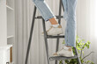 © Pixel-Shot - Legs of woman climbing on stepladder in room