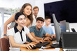 © JackF - Young girl stands behind sitting students of computer courses of web designers, looks at monitor screen and helps in execution of teamwork writing program