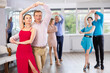 © JackF - Smiling modern woman and man dancing slow ballroom dance during group class in choreography studio....