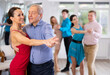 © JackF - Portrait of positive adult pairs of different ages enjoying tango in modern dance hall together