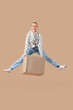 © Pixel-Shot - Young woman with parcel box jumping on beige background