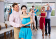 © JackF - Smiling modern woman and man dancing slow ballroom dance during group class in choreography studio....