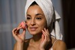 © Vlad - Close up of Caucasian young attractive woman with towel on head using microcurrent facial toning device at home. Beauty device. Beautiful happy female using skincare device