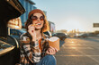 © SHOTPRIME STUDIO - Woman eating fries by car in parking at sunset, smile with sunglasses and beanie in golden hour glow, candid lifestyle portrait conveying authenticity, mindful living and emotional storytelling.