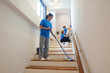 © Natee Meepian - Stair Cleaning. Young woman mopping stairs in bright interior.