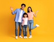 © Ami - Joyful family poses together against a vibrant yellow backdrop