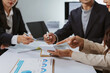 © amnaj - Business colleagues collaborating, calculating finances, and discussing reports with charts and graphs during a corporate meeting in an office