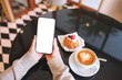 © Farknot Architect - Top view mockup image of a woman holding and using mobile phone with blank desktop screen in cafe