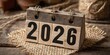 © Syphachan - Wooden 2026 Calendar: An up-close view of a rustic wooden calendar block displaying the year 2026, set against a backdrop of organic textures.