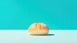 © Дмитрий Петров - A single, golden-brown bread roll sits on a light blue surface against a bright turquoise background.