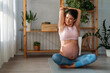 © NDABCREATIVITY - A calm beautiful fit pregnant woman in a peaceful state practicing prenatal yoga in her bedroom