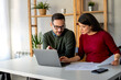 © NDABCREATIVITY - Husband and wife doing paperwork together, paying taxes online on notebook computer