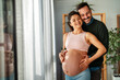 © NDABCREATIVITY - Man in love hugs his pregnant wife, they are waiting together for the baby's arrival. Love, family