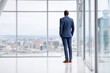© id512 - Rear view of corporate executive in navy suit looking out office window at city skyline