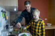 © Siniehina - Father and son preparing a meal together in a kitchen. Parent teaching a child everyday skills, shared activity, healthy food habits, warm bonding moment, natural lifestyle scene.