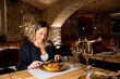 © BGStock72 - Woman enjoys meal in restaurant with warm lighting and brick architecture