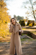 © BGStock72 - Woman smiles while talking on her phone in a sunny park during fall