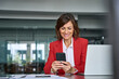 © Stock 4 You - 40s middle aged business woman holding mobile cell phone cellphone in office. Focused mature professional ceo entrepreneur businesswoman using smartphone for work sitting at desk workplace. Copy space
