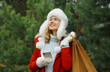© rohappy - Happy smiling woman with phone, shopping bag in winter against Christmas tree, girl using smartphone
