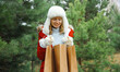 © rohappy - Happy smiling young woman with shopping bag in winter against Christmas tree, snow, holiday shopping