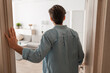 © Prostock-studio - A young man stands in the doorway of his new apartment, casually dressed. He gazes at the modern interior design as he prepares to step inside and explore the space.
