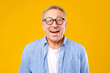 © Prostock-studio - A man stands in front of a bright yellow background, wearing glasses and a checked shirt. He has a big smile, showing happiness and joy. It looks like a cheerful moment.