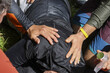 © CoreRock - Close up urgent rescue scene showing helping hands on back of injured person with care and concern, teamwork providing emergency first aid support to victim lying on ground during outdoor crisis