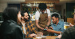 © WesJVR/peopleimages.com - Waiter, man and phone with payment at pub for beer purchase, paperless transaction or drinking. Friends, people or server with POS machine in bar for easy banking, drinks checkout or social gathering