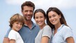 © Thares2020 - A happy family of four parents and two children smiling together outdoors against a clear blue sky