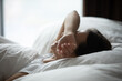 © fizkes - I hate waking up early. Side view sleepy lazy young woman lying in comfortable bed hide closed eyes beneath arm avoid morning sun pretend nap protect herself from daylight wish to prolong sweet sleep