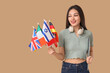 © Pixel-Shot - Female Asian student with flags of different countries and laptop on beige background