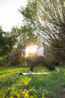 © leungchopan - Woman practicing yoga in green park