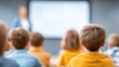 © liliyabatyrova - Brightly dressed students sit attentively in a classroom, focusing on their teacher as she shares information on a large screen, igniting their passion for learning