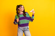 © deagreez - Young woman with colorful striped sweater smiles while holding a triangle snack backpack casual lifestyle shot against a bright yellow background