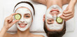 © Facundo - Happy young couple enjoying home spa treatment, lying down with white clay face masks and holding fresh cucumber slices over their eyes