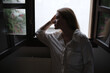 © ADDICTIVE STOCK - Woman in thoughtful silhouette by window in low light