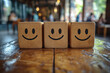 © Vladan - Four wooden cubes with simple smiley faces stand in a neat row on a rustic wooden table indoors, with a softly blurred background creating a warm, cheerful mood.