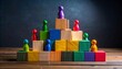 © Shoaib - Colorful peg people on a wooden block pyramid with a leader at the top representing organizational hierarchy career success and leadership competition