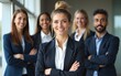 © George - A confident female business leader with his arms crossed, standing looking at the camera, with his team behind him, in an office environment. High quality