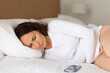© Anastasiya - Adult woman lying on side in bed holding stomach, experiencing abdominal pain at home. Health discomfort concept, illness awareness, lifestyle realism, and calm bedroom environment