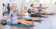 © JackF - Group of elderly people in sportswear exercising Pilates with soft balls while sitting on mats in fitness studio