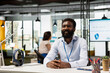 © DC Studio - Smiling black male professional sitting confidently with hands crossed at corporate office desk. Positive business portrait of african american man, representing professionalism and workplace success.