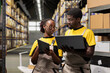 © DC Studio - Workers team in overalls documenting inventory in an industrial warehouse, writing shipment protocols on devices. Working on parcel handling and merchandise storage in large scale depot.